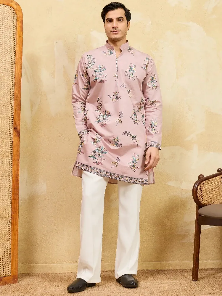 Man wearing a mauve floral print ethnic kurta with white trousers