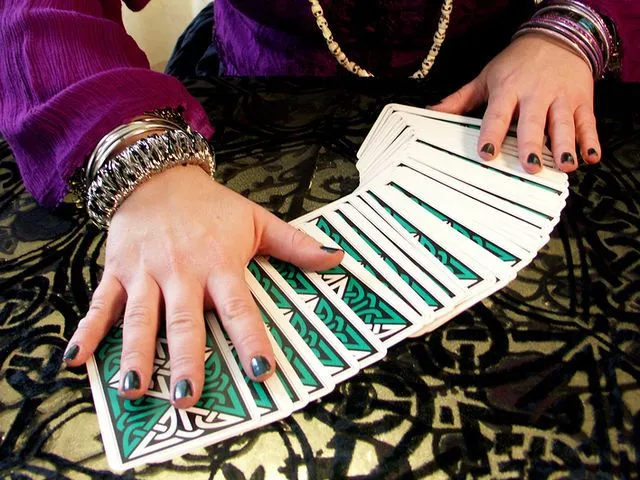 This may contain: a woman with her hands on top of a tarot card reading nyc board game