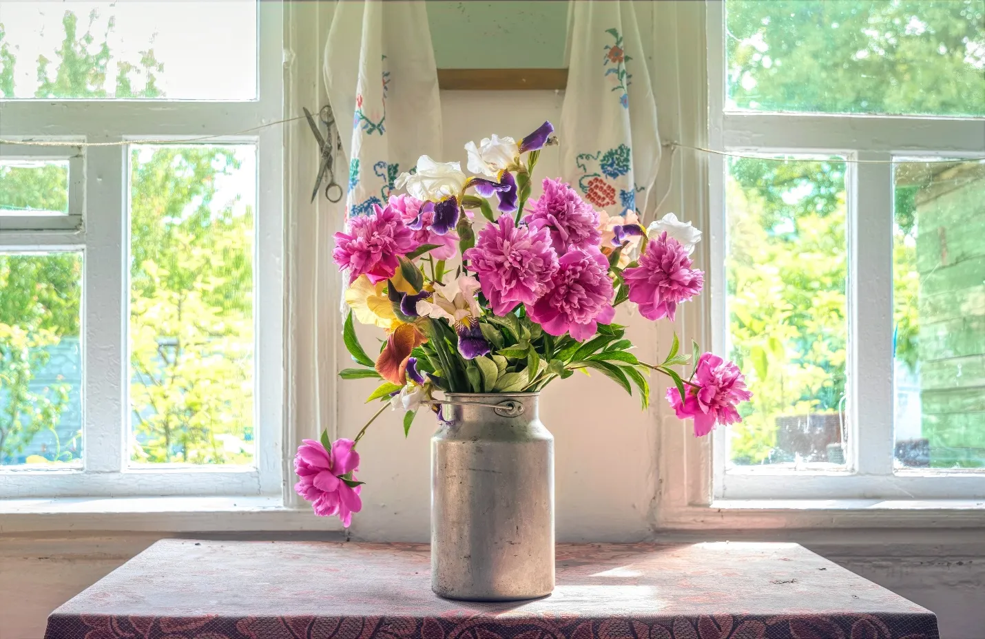 A floral table centerpiece in front of large windows filled with sunlight