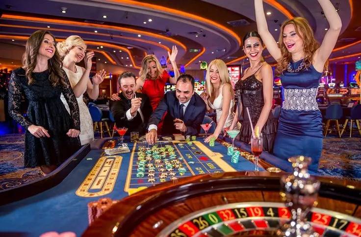 This may contain: a group of people standing around a casino table
