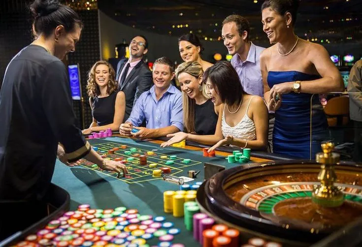This may contain: a group of people standing around a casino table