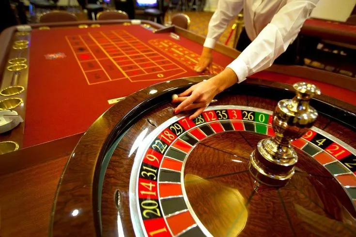 This may contain: a man is playing roulejack at a casino table with his hand on the wheel