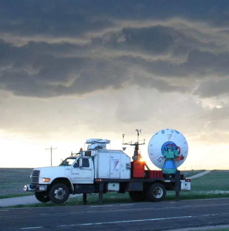 This may contain: a white truck with a satellite dish on the back of it's flatbed