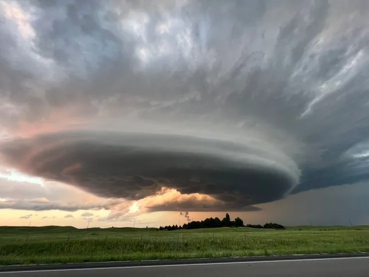 This may contain: a large cloud looms over an open field