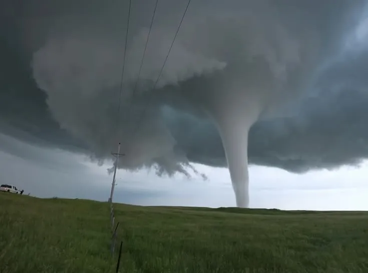 This may contain: a large tornado cloud is in the sky over a field