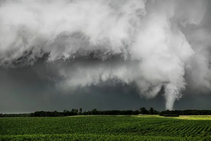 This may contain: a large storm cloud is coming in over a green field