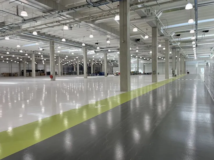 This may contain: an empty warehouse with white and yellow lines on the floor, lights hanging from the ceiling