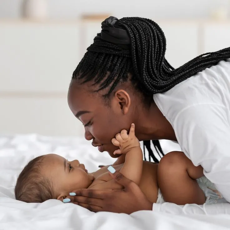 This may contain: a woman laying on top of a bed next to a baby